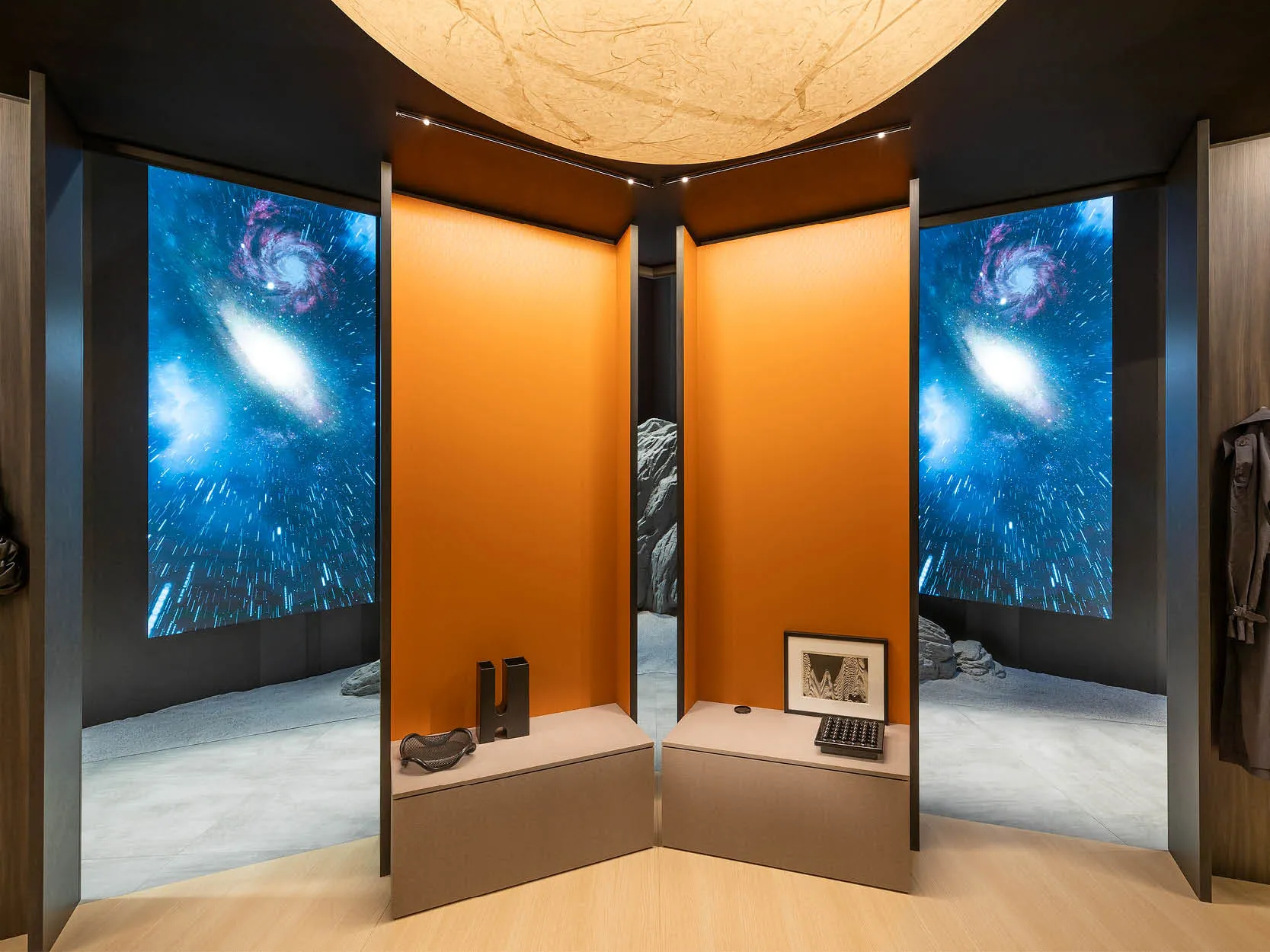 CLEAF 展間搭配暖橘與深灰對比牆面，背景為星空意象投影與岩石裝置，創造沉浸式探索氛圍。