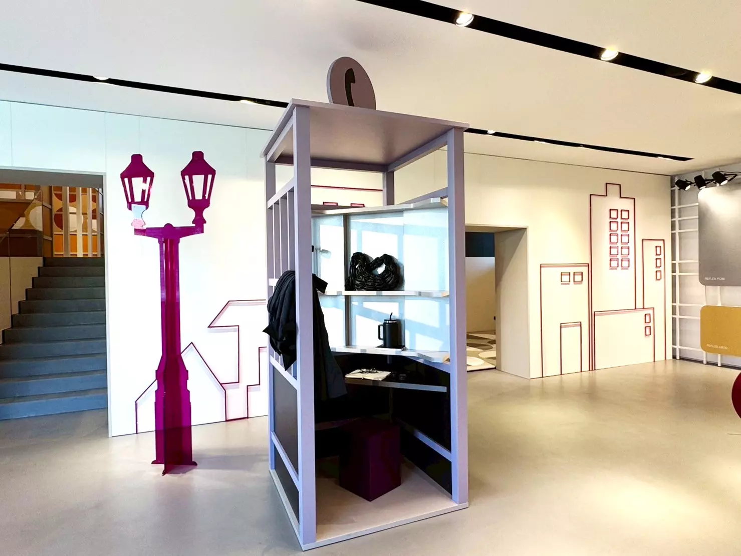 CLEAF 展示空間中的淺紫色立式展示櫃，內部陳列包包與飾品，搭配牆面上的紫紅街燈與城市輪廓插畫，營造城市生活場景與產品應用情境。