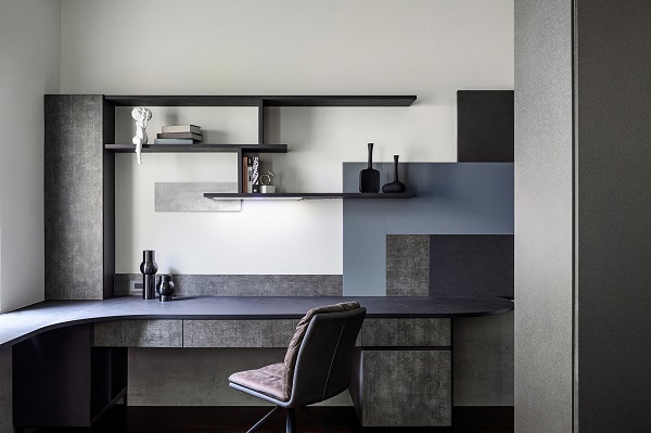 深灰色調書桌以 EGGER 塑合板材質製作，搭配懸掛收納層板與幾何拼接設計，營造俐落現代感，適合居家工作或學習空間，兼顧功能與美觀。