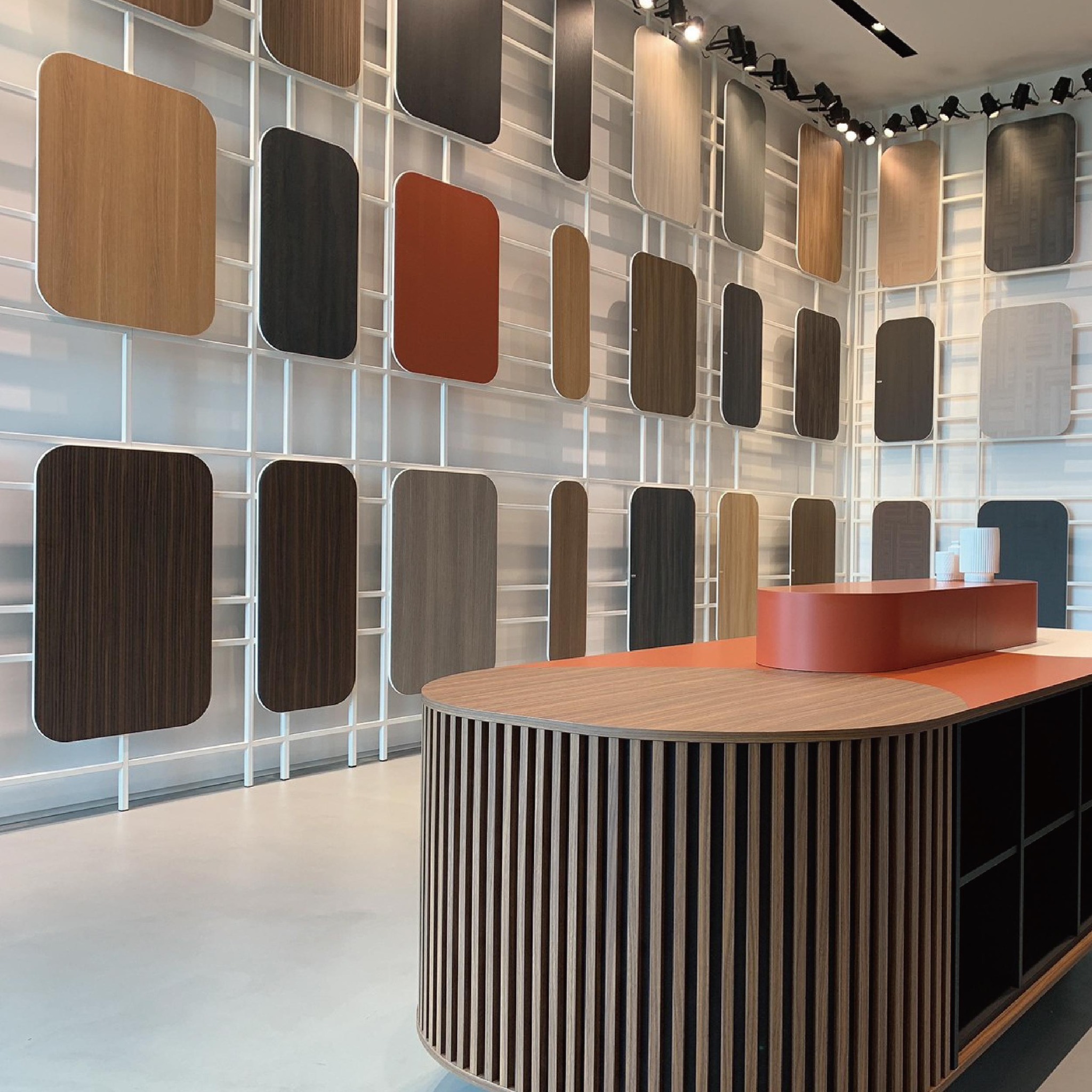 CLEAF 展區牆面展示多款不同紋理與色系的樣板，整齊排列於網格結構上，中央搭配弧形櫃台，強調材質選擇的豐富性。