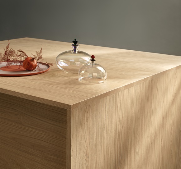 EGGER 淺色木紋塑合板打造的簡約桌面，搭配玻璃擺飾，展現自然與現代風格的融合。