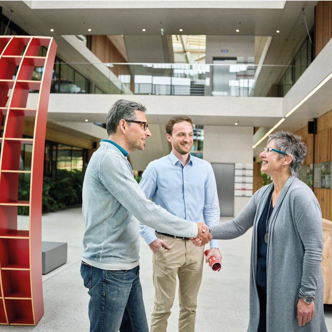 圖為 EGGER 辦公室中三人會面握手，象徵企業推動永續材料循環與人本關懷。