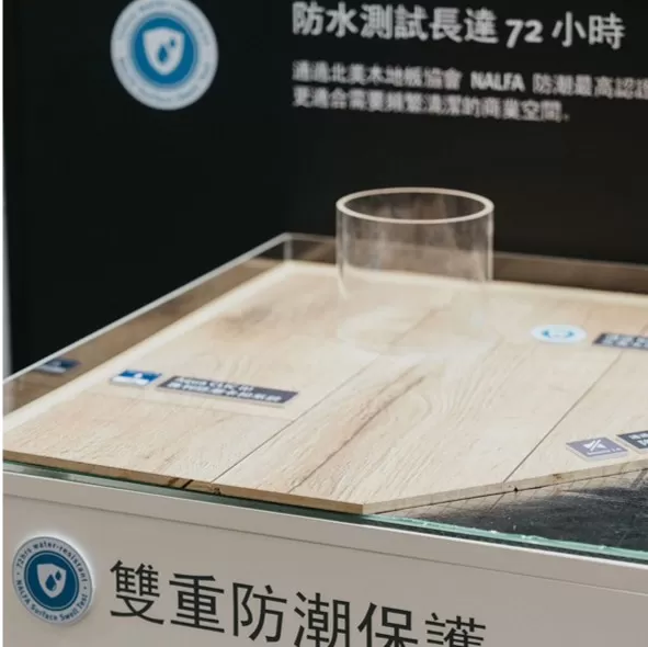 EGGER 雙重防潮保護展示模組，超耐磨木地板表面放置透明水杯，強調其長效防潮測試與優異防水性能。