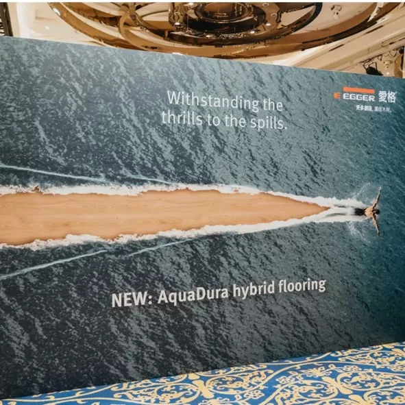 EGGER AquaDura 系列主視覺，強調產品具備防潮與耐磨特性，圖像設計為木紋地板劃破水面的動感場景。